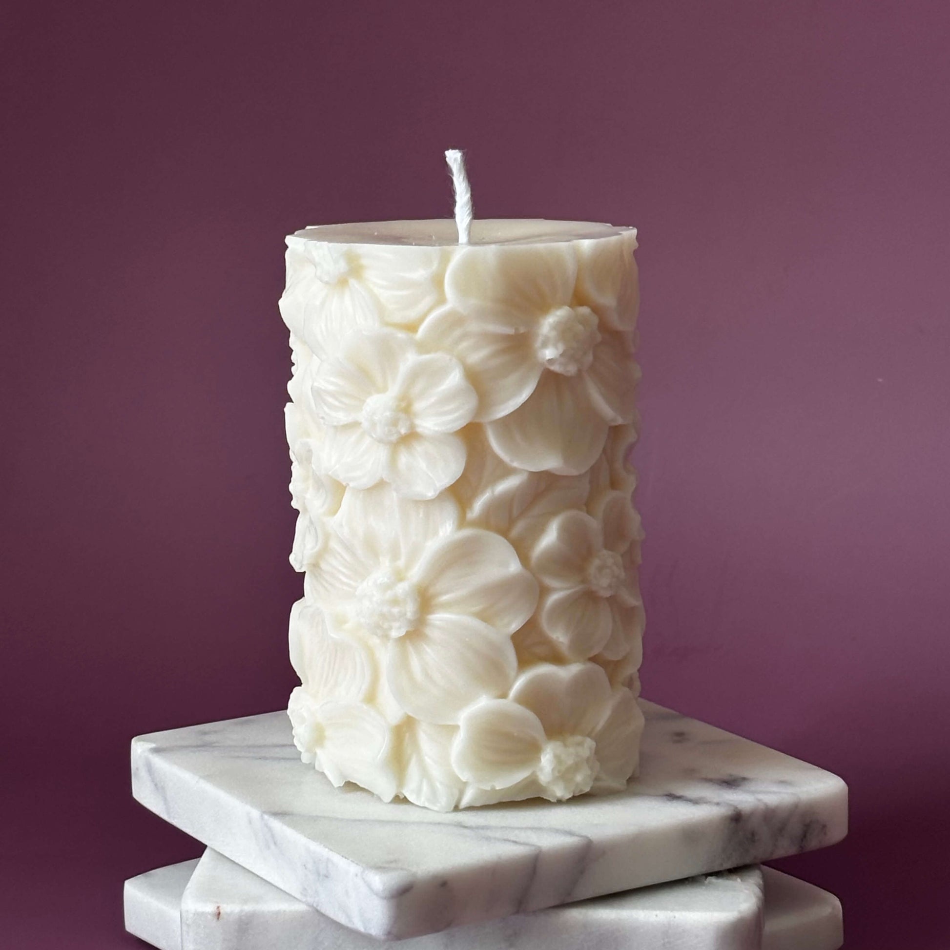 Unlit floral soy pillar candle on stacked marble coasters – decorative home accent	