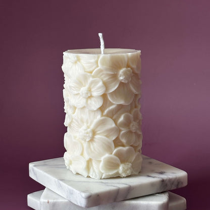 Unlit floral soy pillar candle on stacked marble coasters – decorative home accent	