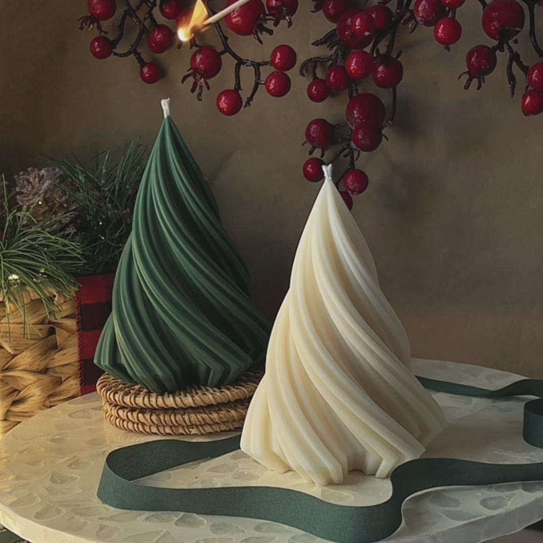 Lighting up handmade spiral tree-shaped candles in green and ivory, with holiday berries and ribbon in the background — perfect for Christmas or winter home decor