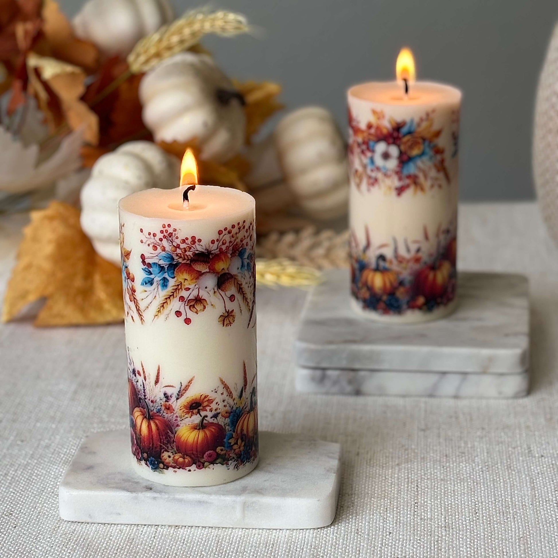 Two pumpkin holiday candles glowing with autumn floral design, cozy fall decor centerpiece for Thanksgiving table and seasonal home decoration.