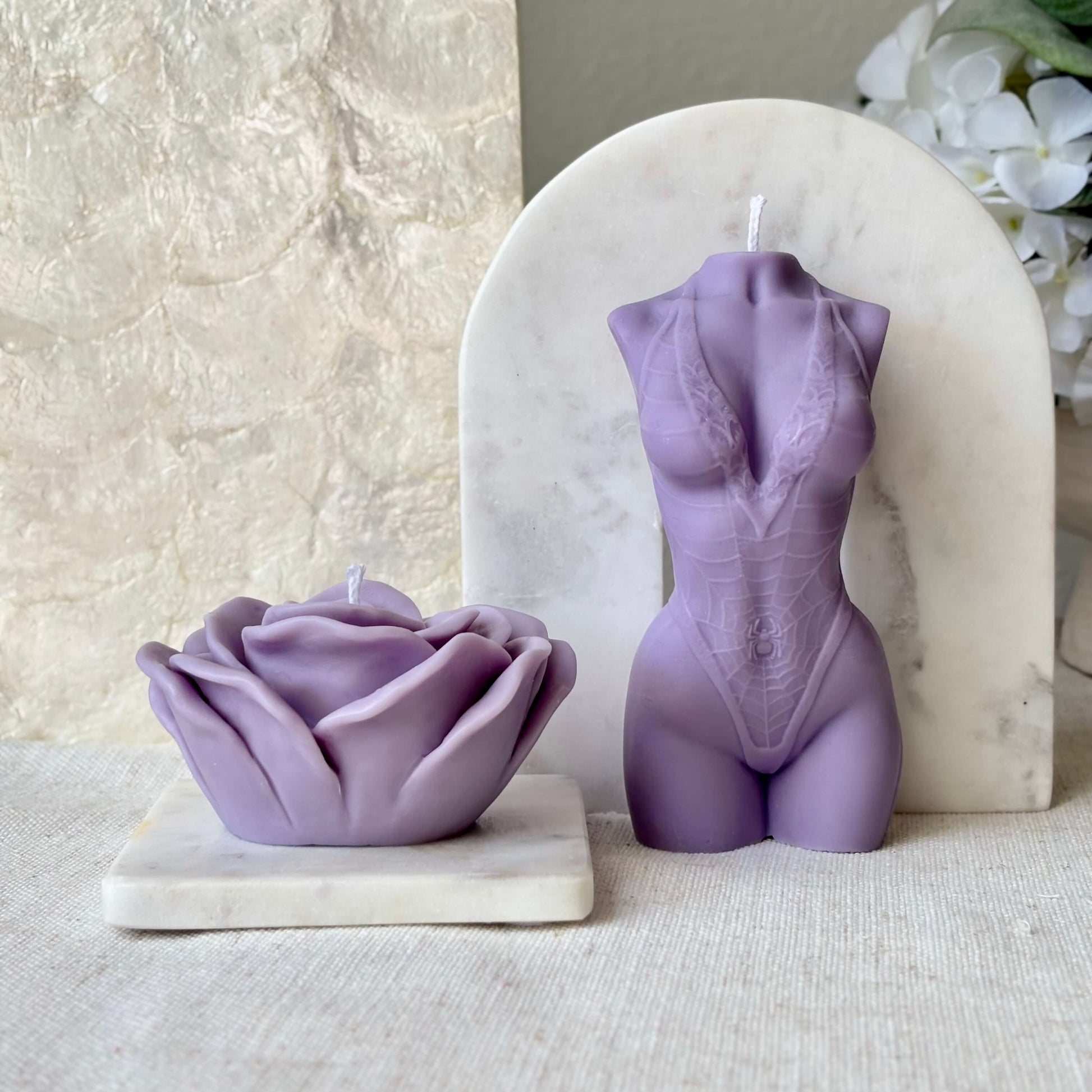 Purple soy wax torso candle and rose shaped candle on marble bases for elegant home decor