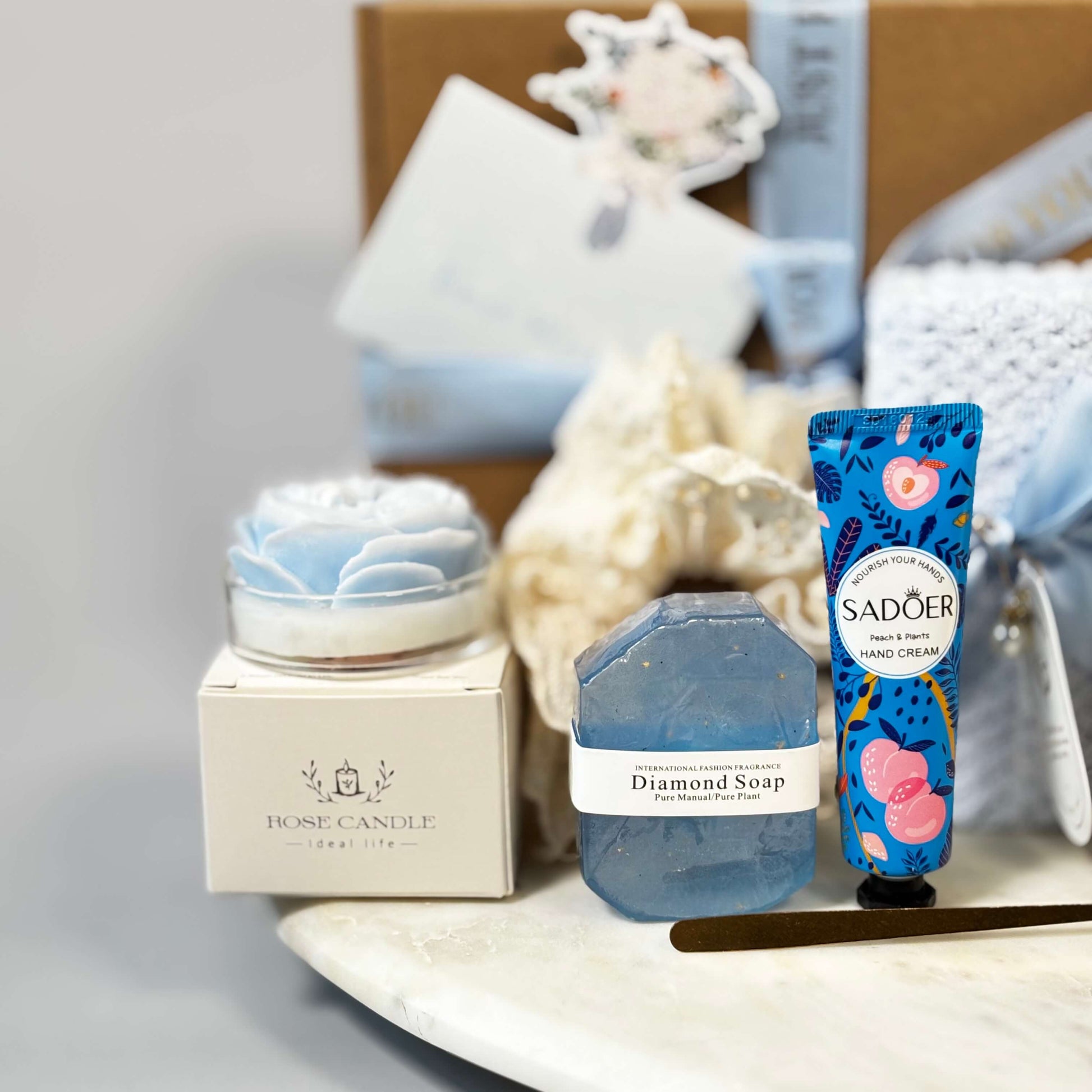 Close-up of a relaxing spa gift set for women with blue diamond soap, rose-shaped soy candle, and peach hand cream – perfect for self-care and beauty gift boxes.
