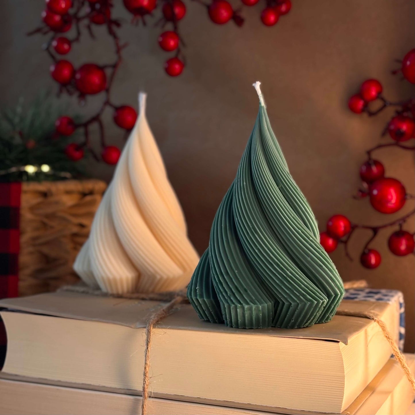 Green and ivory handmade candles in Christmas tree form, styled on vintage books with berry background, perfect gift idea

