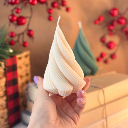 Cream twisted tree candle held in hand, ideal as Thanksgiving gift or Secret Santa present, cozy table decor with festive red berry background


