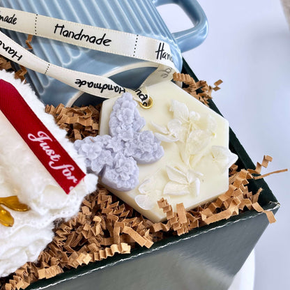 Close-up of handmade floral wax sachet with lavender butterfly detail, nestled in shredded paper inside a luxury gift box — perfect for relaxation, spa gifts, or thoughtful surprises